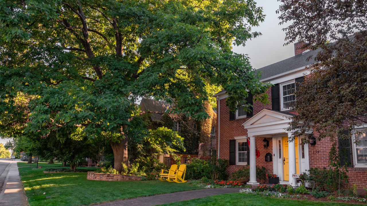 Red brick home with white portico and yellow door in the Hilltop neighborhood of Denver, Colorado